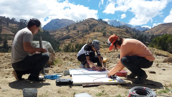 Three people crouched down working on assembling a solar panel