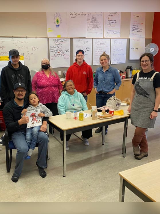 A group of people posing around a table in a classroom