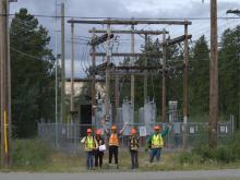 YukonU Northern Energy Innovation students and staff stand in front of a electrical sub-station